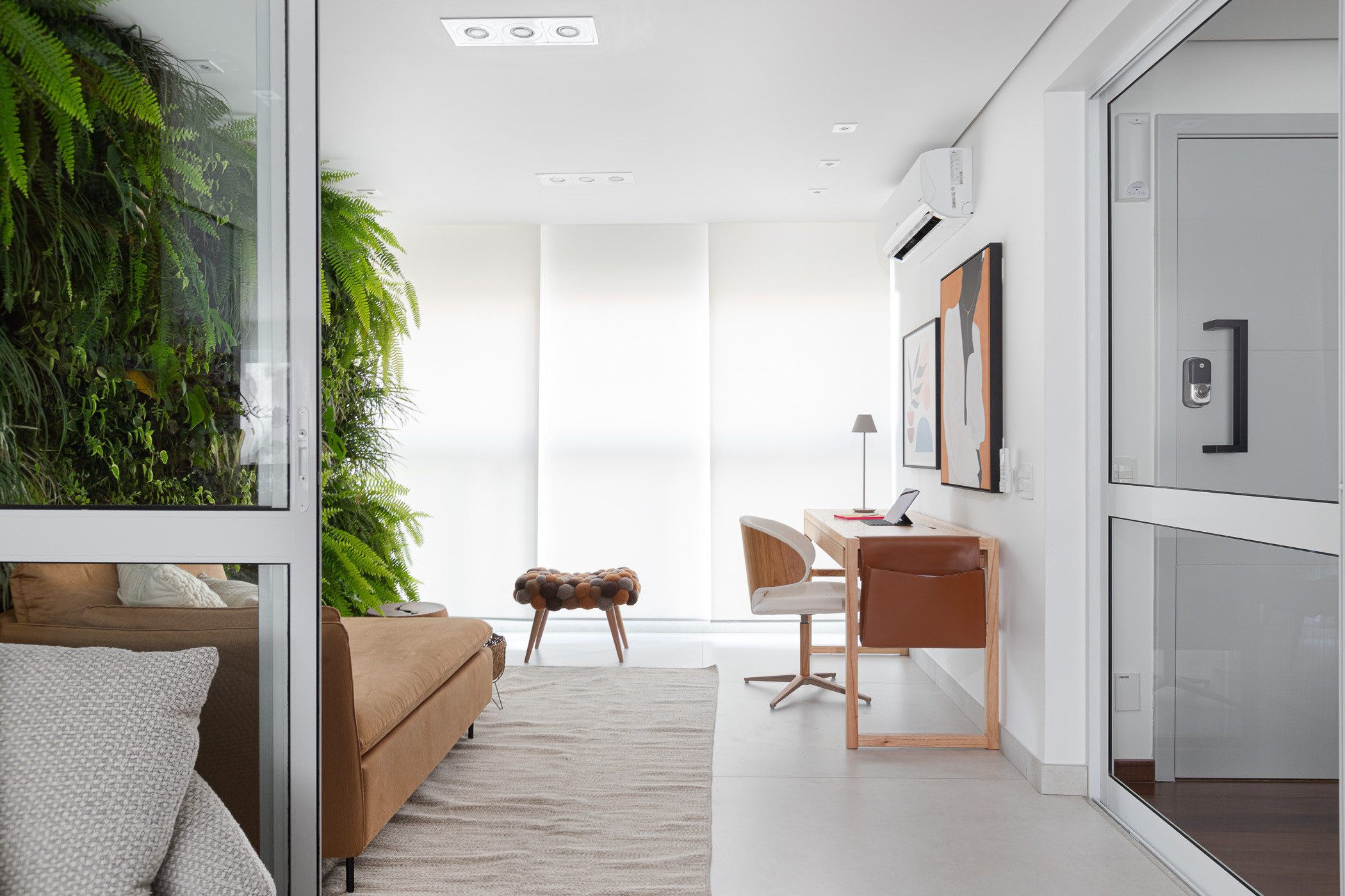 Ambiente de estudo com parede verde natural, mesa de madeira e cadeiras confortáveis, com luz natural abundante